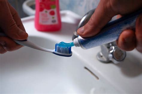 Premium Photo Human Hands Squeeze A Blue Toothpaste Onto A Blue