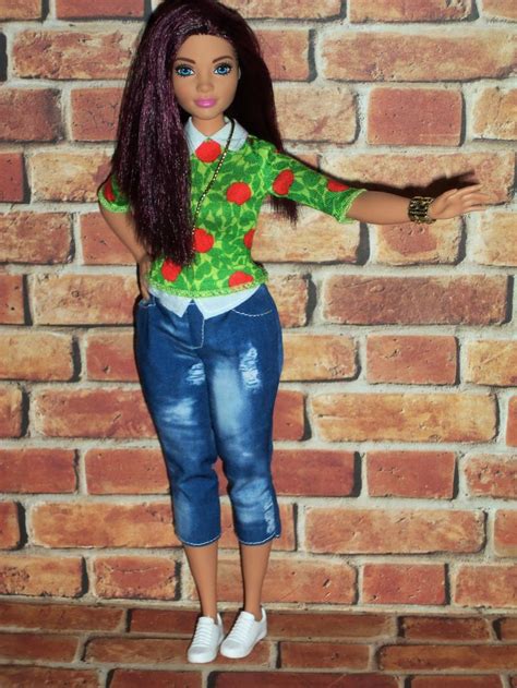 A Doll With Long Hair Is Standing In Front Of A Brick Wall Wearing Jeans And A Green Shirt