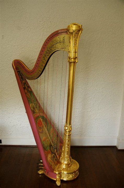 A Gold Colored Harp Sitting On Top Of A Wooden Floor Next To A White Wall