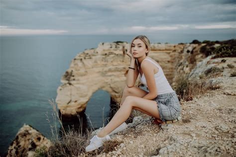 Jeune Femme Blonde Assise Sur Le Dessus Des Rochers Au Bord De L Oc An Photo Gratuite