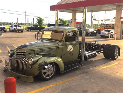 An Old Green Truck Parked At A Gas Station