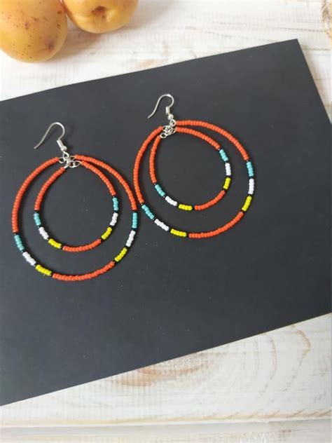 Two Pairs Of Colorful Beaded Hoop Earrings Sitting On Top Of A Wooden