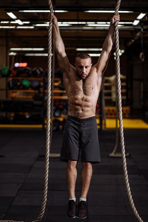 Serious Young Man Is Concentrated On Hanging Exercise On Ropes Stock