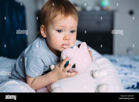 Little Child Is Having Fun Playing With Soft Toys On The Couch At Home