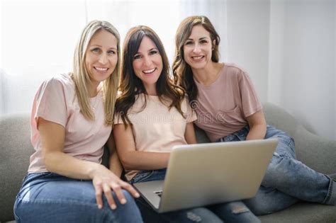 Smiling Best Girl Friends Blond And Brunette Sit On Sofa With Laptop