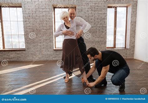 Helpful Mature Dance Instructor Teaching Aged Couple In The Ballroom