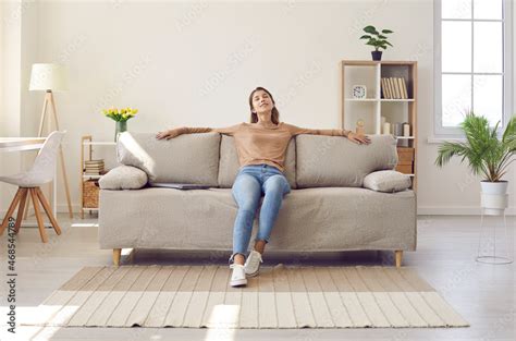 Happy Relaxed Young Woman Resting Sitting On Comfortable Sofa In Living