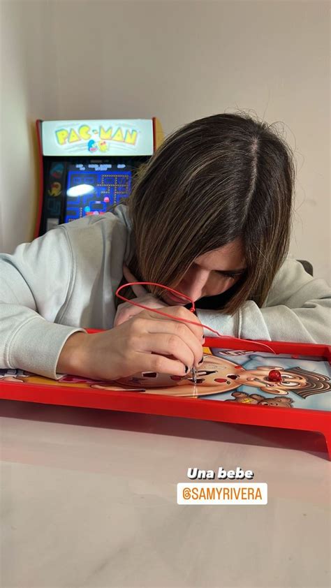 A Person Sitting At A Table With A Game In Front Of Her And Writing On