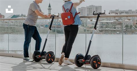 Two People Riding Segways Near The Water