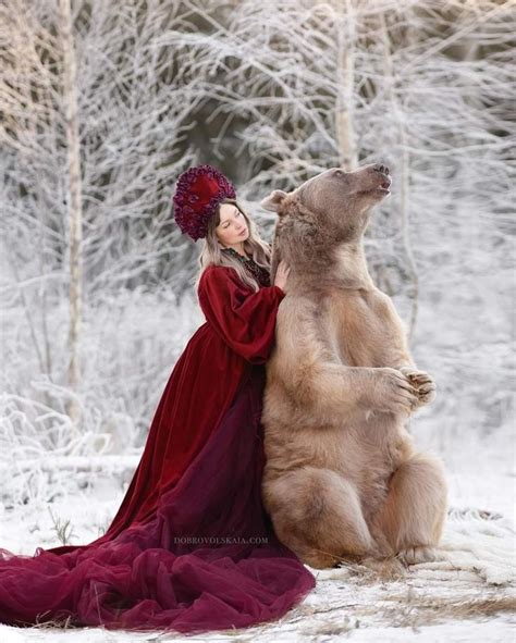 A Woman In A Red Dress Is Standing Next To A Brown Bear