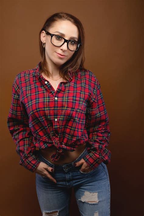 Smiling Brunette In Glasses Posing With Her Hands In Her Jeans Pockets And Looking At The Camera