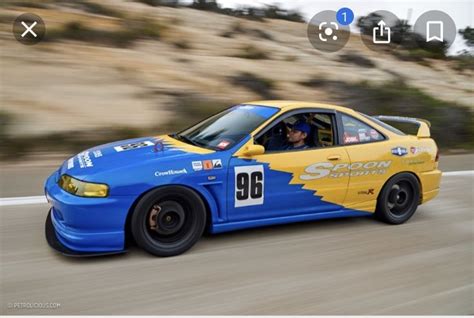 A Blue And Yellow Race Car Driving Down The Road