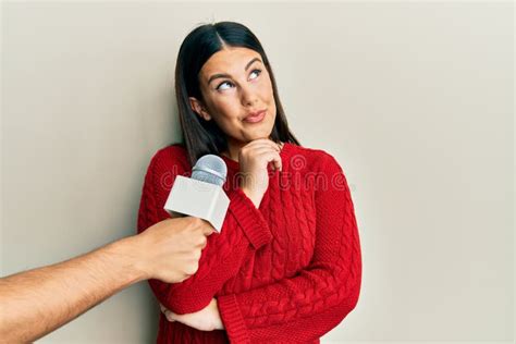 Beautiful Brunette Woman Being Interviewed By Reporter Holding Microphone Thinking Concentrated
