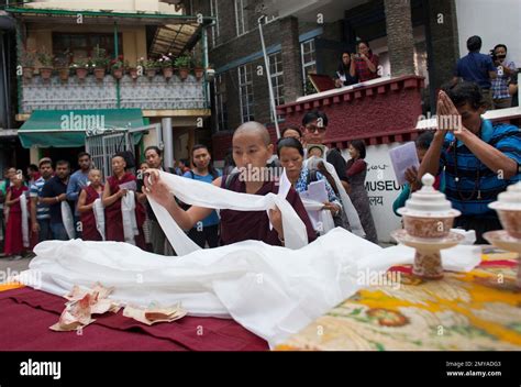 An Exile Tibetan Buddhist Nun Offers A Ceremonial Scarf In Front Of A