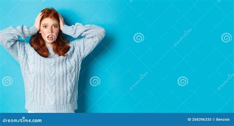 Nervous Redhead Girl Standing Overwhelmed Holding Hands On Head In Panic And Staring At Camera