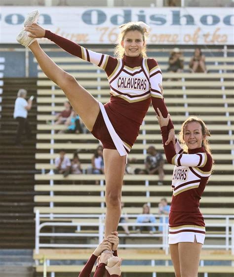 Two Cheerleaders Are Doing Tricks On The Field