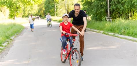 Padre Cari Oso Ense Ando A Su Hija A Andar En Bicicleta Foto Premium