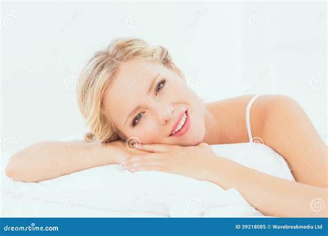 Attractive Young Blonde Lying On Her Bed Smiling At Camera Stock Image