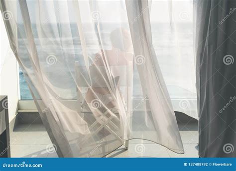 Naked Beautiful Female In The Bikini Sitting On A Chair Behind The Transparent Waving Curtains