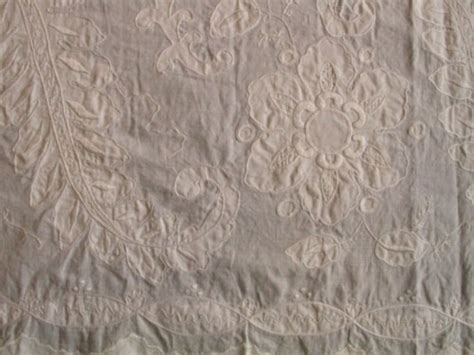 An Old White Table Cloth With Flowers And Leaves On It