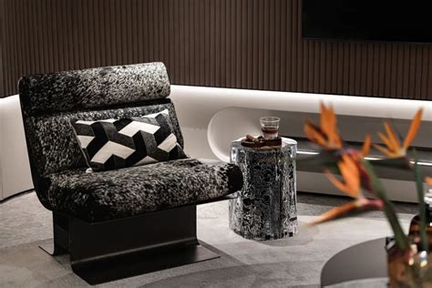 A Black And White Chair Sitting Next To A Vase With Flowers On Top Of It