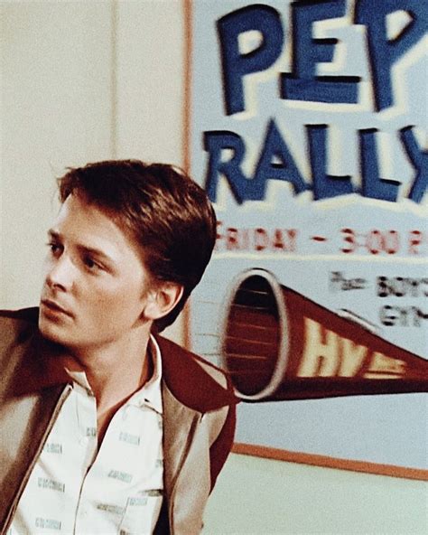 A Man Is Standing In Front Of A Sign That Says Pep Rally On The Wall