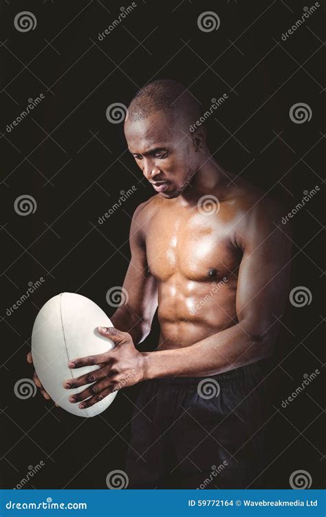 Concentrated Shirtless Athlete Looking Down While Holding Rugby Ball