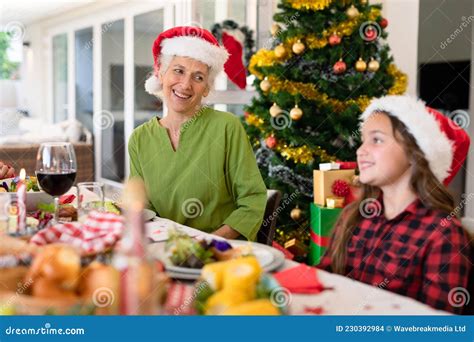 Happy Caucasian Grandmother And Granddaughter Wearing Santa Hats