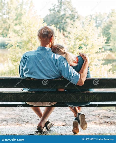 Rear View Of Romantic Senior Couple Hugging On A Park Bench Stock Image