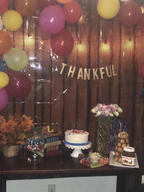 a table topped with lots of cake and balloons in front of a thank you sign