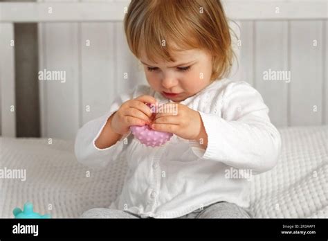 Petite fille mignonne jouant des balles tactiles à boutons La main d