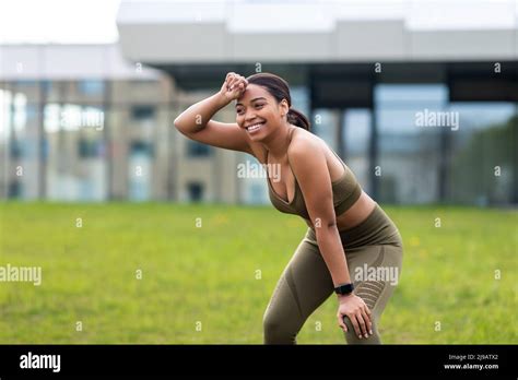 Happy Tired Young Black Woman Wiping Sweat From Forehead After Jogging