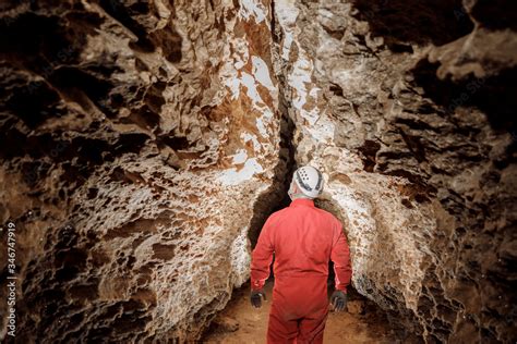 Man walking and exploring dark cave with light headlamp underground ...