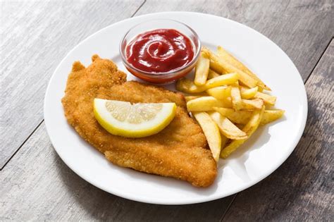 Escalope vienés con patatas fritas en madera Foto Premium