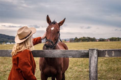 Mulher Usando Chapéu De Cowboy Batendo Seu Cavalo No Rancho Imagem de