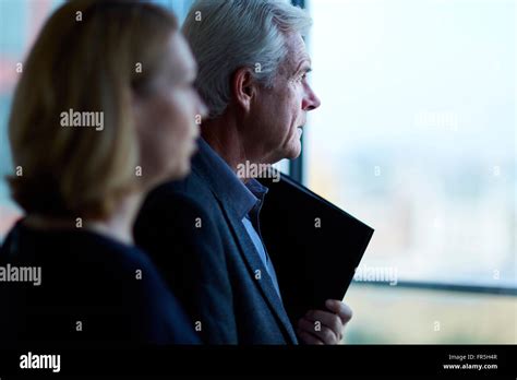 Pensive Businessman And Businesswoman Looking Through Window Stock