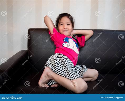 Petit Bout Droit Asiatique D Enfant De Fille D Enfant Sur Le Sofa Photo