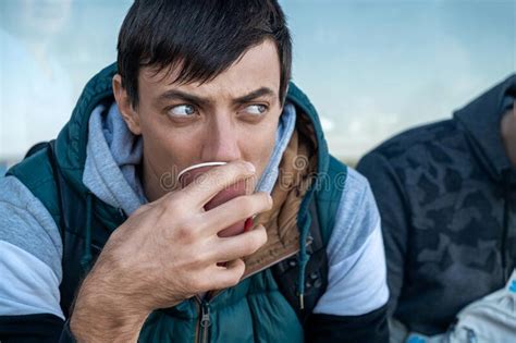 Serious Brunette Man Drinking Coffee Or Tea From Disposable Paper Cup