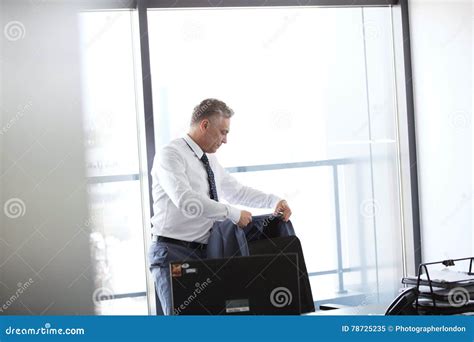 Mature Businessman Hanging Jacket On Back Of Office Chair Stock Image