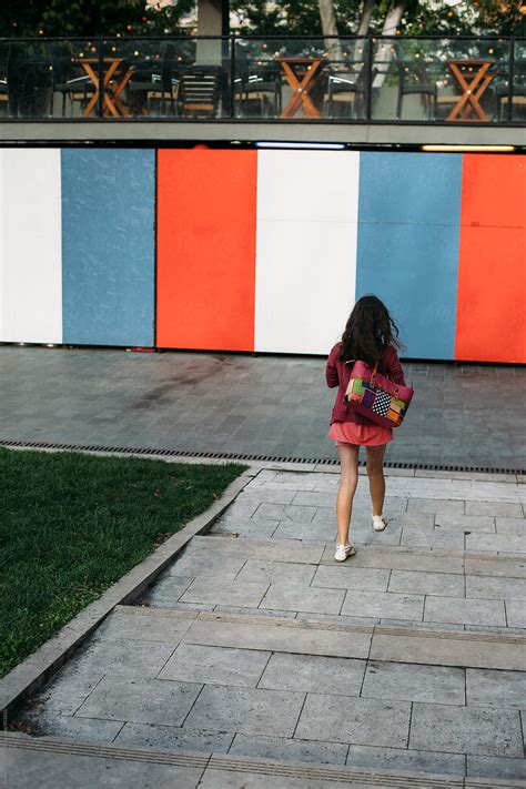 Preteenager Girl Walking Away On The Stairs Towards A Striped Wall