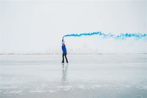 A Caucasian Woman Is Skating On A Frozen Lake Holding Colored Blue