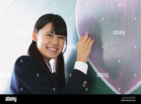 Japanese High School Student Writing On Classroom Blackboard Stock