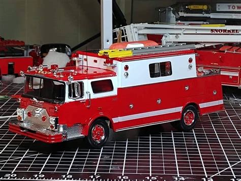 Two Red And White Fire Trucks Sitting On Top Of A Tiled Floor