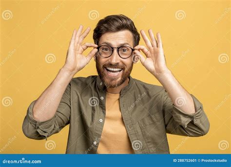 Excited Middle Aged Man Touching His Glasses And Smiling At Camera