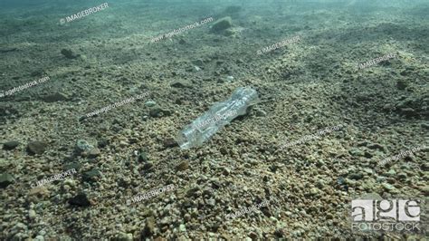 Close Up A Plastic Bottle Lies On The Seabed In The Sun Rays In The