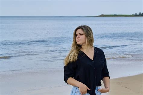 Model Blonde Girl With Black Shirt And Blue Jeans Posing In The Sea