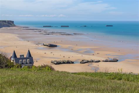 Arromanches-les-Bains beach with the remains of the Mulberry harbour in Normandy, France - The ...