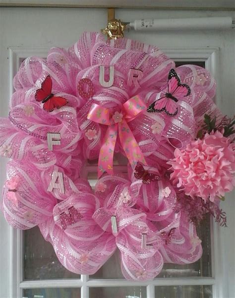 A Pink Wreath With Butterflies And Flowers Hanging From The Side Of A