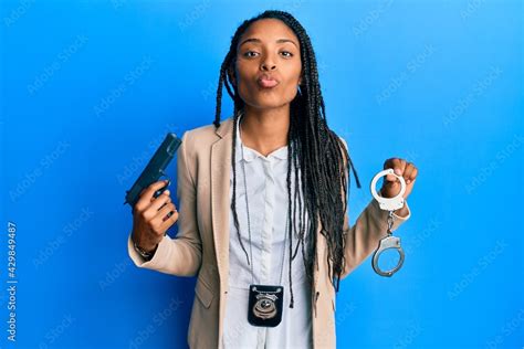 African American Police Woman Holding Gun And Handcuffs Looking At The