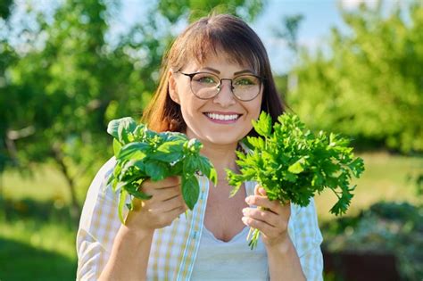 Mujer feliz con cosecha de hierbas aromáticas frescas con manojo de